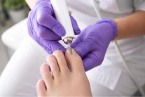 Behandeling van een teennagel met handschoenen tijdens een gespecialiseerde pedicure